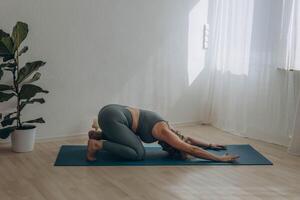 een 50 jaar oud vrouw doet yoga Bij huis foto