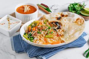 groente biryani met raita en saus in een schotel geïsoleerd Aan servet kant visie Aan grijs achtergrond beroemd Indisch en Pakistaans voedsel foto
