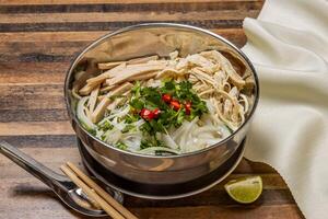 versnipperd kip en worst pho topping met noedels, voorjaar ui, rood Spaanse peper, koriander en eetstokjes geserveerd in kom geïsoleerd Aan houten tafel top visie van hong Kong snel voedsel foto