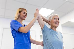 dokter of fysiotherapeut werken onderzoeken behandelen gewond arm van senior vrouw geduldig, uitrekken en oefening, aan het doen de revalidatie behandeling pijn in kliniek. foto