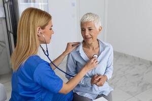 zorgzaam vrouw dokter gebruik phonendoscope onderzoeken senior geduldig hart tarief Bij overleg in ziekenhuis. vrouw verpleegster of gp gebruik stethoscoop luister naar vrouw hartslag in kliniek. foto