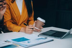 mooie jonge glimlachende aziatische zakenvrouw die op laptop werkt en koffie drinkt, azië zakenvrouw werkdocument financiën en rekenmachine in haar kantoor. foto