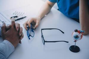 detailopname van Aziatisch vrouw dokter pratend met ouderen geduldig tonen oogbol model- en uitleggen oog ziekte in ziekenhuis foto