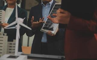 detailopname Bij tablet, ingenieurs richten Bij tablet met hun handen. naar gezamenlijk ontwerp de gebruik van hernieuwbaar energie met wind en zonne- energie. concept van gebruik makend van hernieuwbaar energie. foto