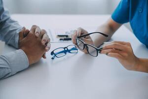 detailopname van Aziatisch vrouw dokter pratend met ouderen geduldig tonen oogbol model- en uitleggen oog ziekte in ziekenhuis foto