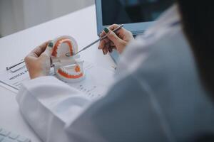 tandartsen bespreken gebitsproblemen bij het rapporteren van röntgenfoto's op het laptopscherm aan patiënten. foto