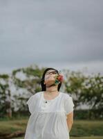 portret van een mooi jong vrouw gekleed in wit jurk Holding roos bloemen foto