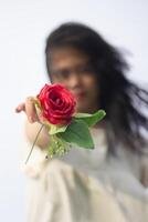 portret van een mooi jong vrouw gekleed in wit jurk Holding roos bloemen foto