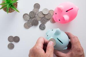 hand- zetten geld munt in varkentje voor besparing geld. foto