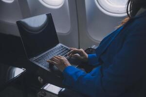 gebruik makend van mobiel en laptop, attent Aziatisch mensen vrouw persoon aan boord, vliegtuig venster, perfect vastleggen de verwachting en opwinding van vakantie reizen. Chinese, Japans mensen. foto