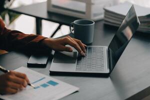 Aziatisch bedrijf vrouw gebruik makend van rekenmachine en laptop voor aan het doen wiskunde financiën Aan een kantoor bureau, belasting, rapport, boekhouding, statistieken, en analytisch Onderzoek concept foto