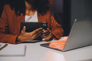 vrouw zittend Bij haar bureau in huis kantoor werken laat Bij nacht gebruik makend van laptop computer vrouw web ontwerper werken na een tijdje foto