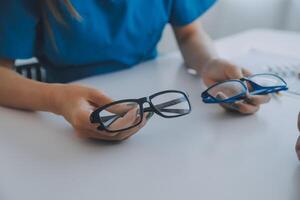 detailopname van Aziatisch vrouw dokter pratend met ouderen geduldig tonen oogbol model- en uitleggen oog ziekte in ziekenhuis foto