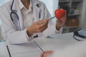 handen van dokter vrouw Holding rood hart, tonen symbool van liefde, menselijk ondersteuning naar geduldig, bevorderen medisch verzekering, vroeg controle voor gezondheidszorg, cardioloog helpen. dichtbij omhoog van voorwerp foto