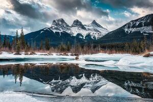 visie van drie zussen bergen met sneeuw gedekt Aan bevroren boog rivier- reflectie in de ochtend- Aan winter Bij Canada foto