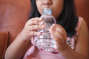 kind drinken fles van water foto