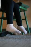 een zacht sokken Aan kind voeten zittend Aan een stoel foto