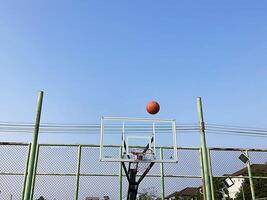 de basketbal vliegt door de lucht naar de hoepel foto