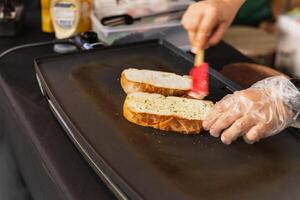 vrouw Koken knoflook brood met en kruiden Aan ijzer pan. foto