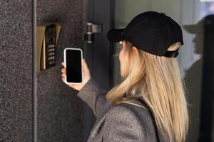 vrouw vergrendeling smartlock Aan de Ingang deur gebruik makend van een slim telefoon. concept van gebruik makend van slim elektronisch sloten met sleutelloos toegang. foto
