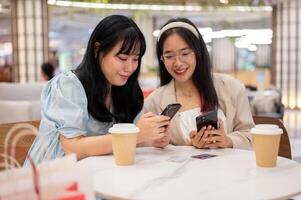 twee Aziatisch vrouw vrienden zijn ontspannende in een cafe in de boodschappen doen winkelcentrum na boodschappen doen samen. foto