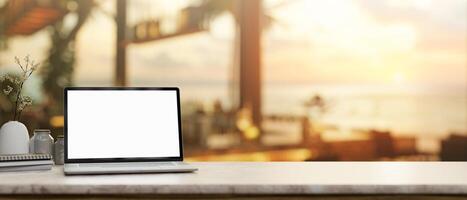 een laptop mockup Aan een tafelblad, met een wazig achtergrond van een aan het strand hotel lounge of restaurant. foto