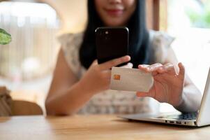 een detailopname beeld van een Aziatisch vrouw registreren haar credit kaart Aan een boodschappen doen app Aan haar smartphone. foto