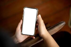 een detailopname beeld van een vrouw gebruik makend van haar smartphone binnenshuis. een wit scherm smartphone mockup foto