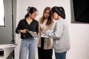 een professioneel Aziatisch vrouw fotograaf pratend met assistenten, voorbereidingen treffen voordat een schieten. foto