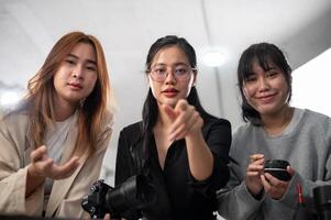 een professioneel Aziatisch vrouw fotograaf en haar team zijn op zoek Bij de camera. foto