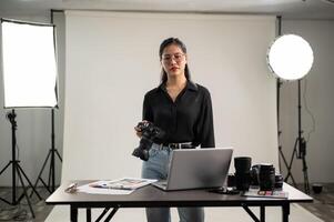 een jong, zelfverzekerd Aziatisch vrouw fotograaf met haar dslr camera in een professioneel studio. foto