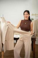 een aantrekkelijk vrouw kleermaker is werken in haar studio, controle haar pak patroon Aan een kleermaker pop. foto