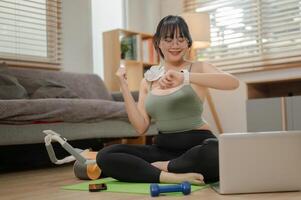 een gezond, gelukkig jong Aziatisch vrouw controle haar verbrand calorieën, zittend Aan een yoga mat. foto