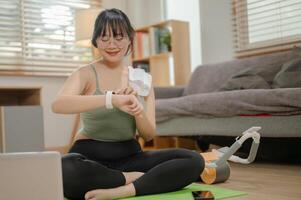 een fit Aziatisch vrouw in sportkleding is controle haar hart tarief en verbrand calorieën Aan haar smartwatch. foto