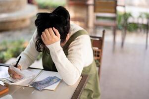 een teleurgesteld en benadrukt Aziatisch vrouw klein bedrijf eigenaar is ervaren een financieel crisis. foto