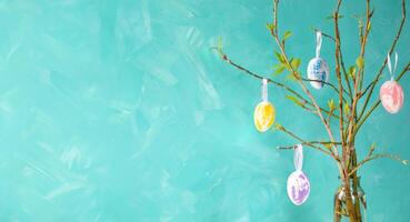 vakantie kaart sjabloon. Pasen boom Aan turkoois achtergrond. kleur eieren hangende Aan voorjaar takjes. foto