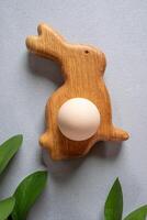 Pasen biologisch beige ei in houten dacht bord net zo konijn, groen bladeren Aan grijs. top visie. dichtbij omhoog. foto