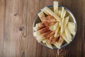 gesneden yam Boon met Chili en limoen in een metaal kom Aan een houten tafel. Mexicaans tussendoortje. jicama. foto