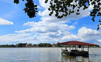 visie van de chao phraya rivier- met huizen of paviljoens overstroomd in rivier- met blauw lucht en wolk achtergrond en Afdeling van boom voorgrond Bij nietthaburi, Thailand. landschap, natuur en bouw. foto