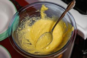 een kom van regelmatig maïsbrood beslag wezen lepelde in koekje papieren foto