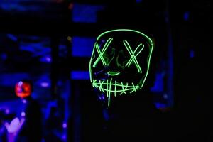 persoon vervelend neon masker in donker kamer foto