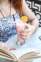 vrouw zittend Bij tafel met boek en drinken foto