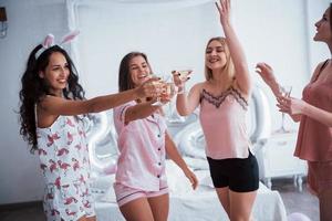 vrienden vieren vrijgezellenfeest in pyjama in de witte kamer bij daglicht foto