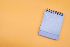 blauw bureau kalender voor juli 2024 geïsoleerd Aan oranje achtergrond. kalender concept met kopiëren ruimte. vlak leggen. foto