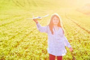 oprecht emoties. gelukkig weinig meisje rennen Aan de veld- met geel speelgoed- vlak in hun handen. foto