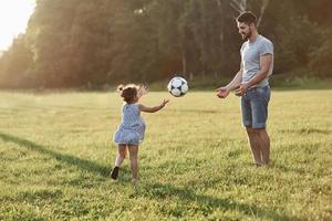 we kunnen soms vals spelen. handen zijn welkom. enthousiaste vader leert dochter hoe hij zijn favoriete spel moet spelen. het is voetbal en zelfs kleine meisjes kunnen het spelen foto