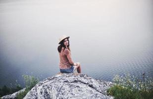 uitzicht vanaf de achterkant. aantrekkelijk toeristisch meisje dat zich voordeed aan de rand van de berg met een helder watermeer op de achtergrond foto
