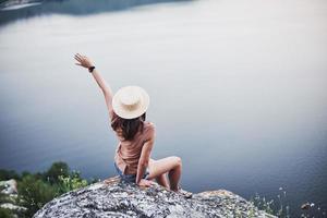 vrijheid voelen. aantrekkelijk toeristisch meisje dat zich voordeed aan de rand van de berg met een helder watermeer op de achtergrond