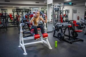 jong sport vrouw vervelend sport slijtage aan het doen oefening met geschiktheid uitrusting Bij Sportschool, ze oefening voor sterk en mooi zo gezond foto