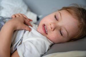 schattig weinig meisje slapen en slijpen tanden in dromen, gebalde tanden met vermoeidheid en spanning. hoog kwaliteit foto